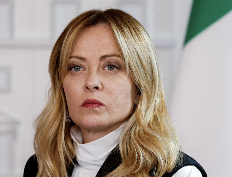 A real press photograph of Italian Prime Minister Giorgia Meloni, the head of state who responded to AI-generated lingerie deepfakes of her in early May 2026 with the four-word principle 'verify before believing, believe before sharing.' This image is authentic, not AI-generated, and represents Meloni in her actual public-facing role rather than the synthetic imagery the post discusses.